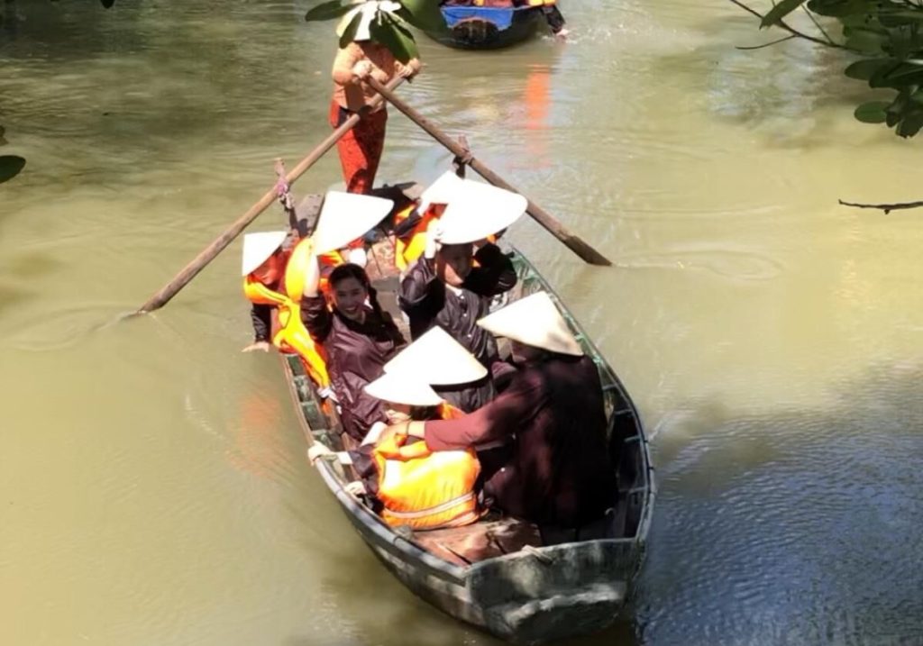 Guests in conical hats rowing a boat on the canal.