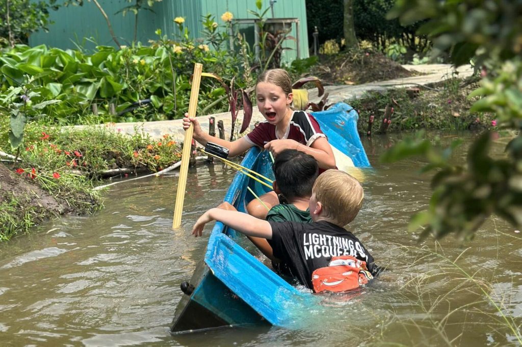 Children paddling a small boat on the canal.