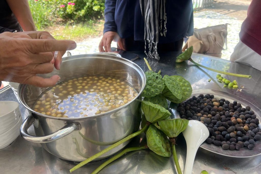 Fresh lotus seeds in a pot, beside lotus seed pods.