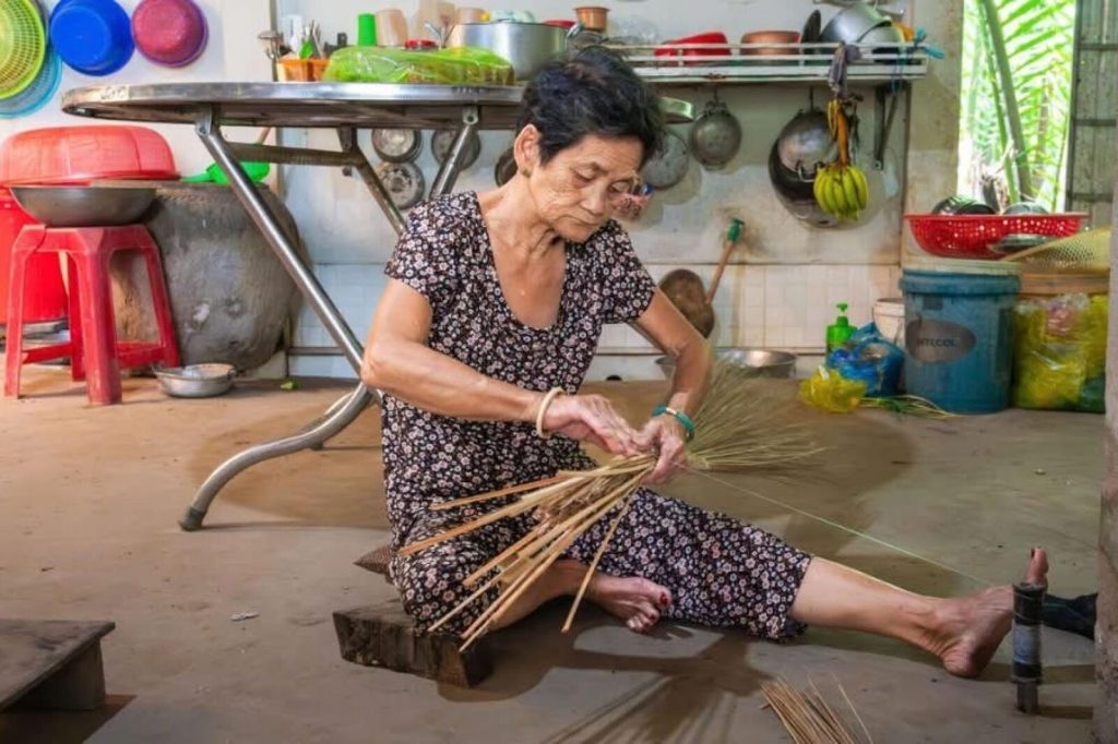 A local woman weaving a broom by hand.