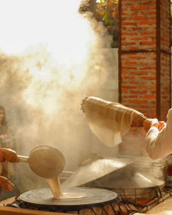 Steam rising as rice paper is made by hand