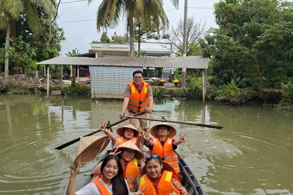 Guests in life jackets paddling a blue boat along the canal.