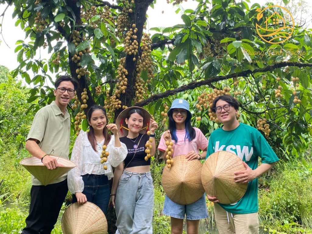 Five young guests holding conical hats under a fruit tree heavy with clusters.