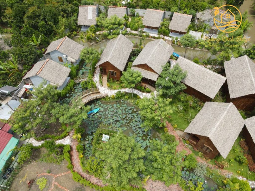 An aerial view of thatched bungalows among garden trees at Mương Đình Lodge.