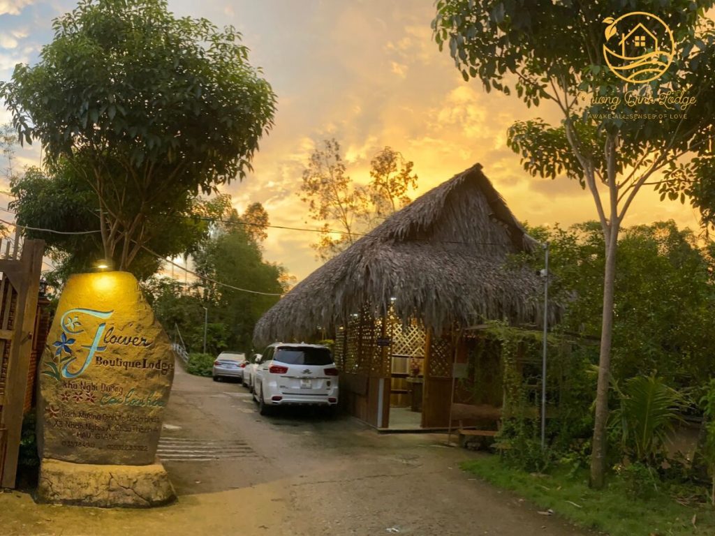 A thatched gatehouse and a large jar sign at sunset, a car parked on the drive.