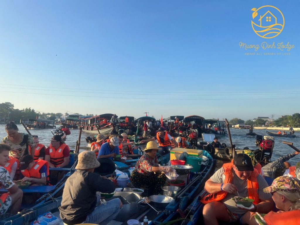 Boats crowded with visitors in orange life jackets on a river in the early morning.