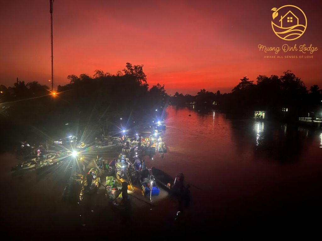 Lit boats on a river under a deep red sky.
