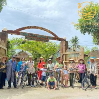 A family group with bicycles under the Homestay Mương Đình gate arch.