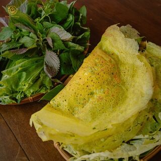 Chiếc bánh vàng giòn bên rổ rau thơm và xà lách.