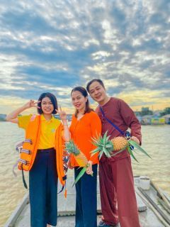 Những người tươi cười cùng trái khóm trên sàn ghe giữa sông.