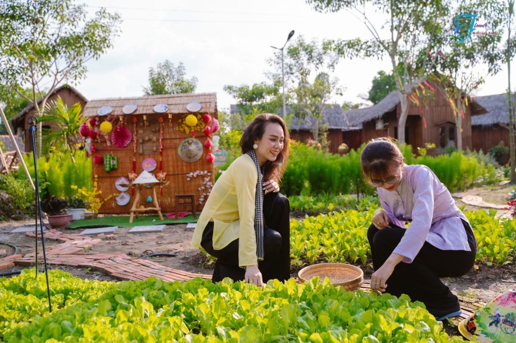 Two women in traditional blouses picking vegetables into a basket.