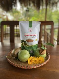 A pack of Minh Nguyen bitter melon tea on a woven tray with green fruit and yellow flowers.