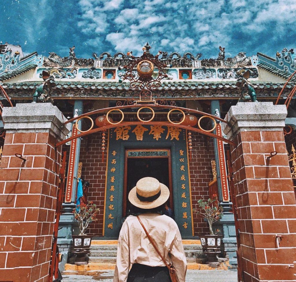 A visitor in a straw hat at the carved entrance of Ông Pagoda.