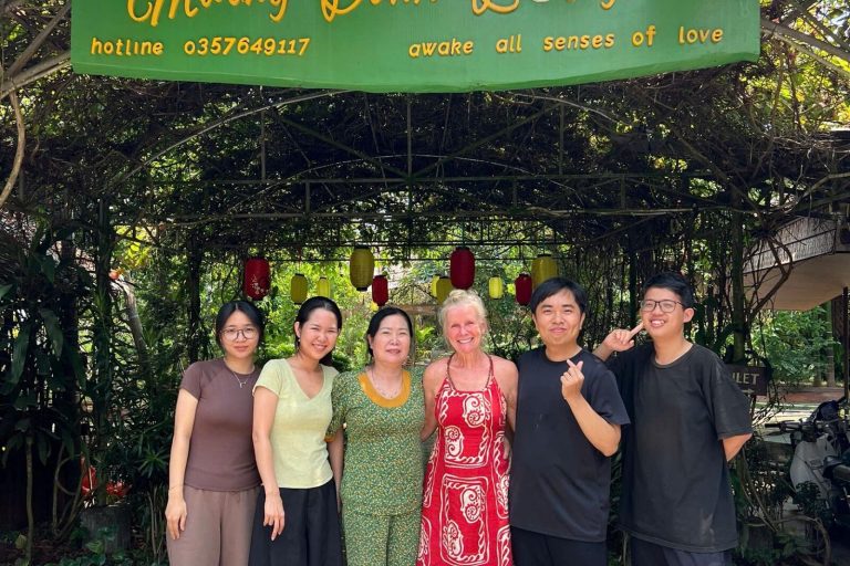 Six smiling people under the green Mương Đình Lodge sign at the garden gate.