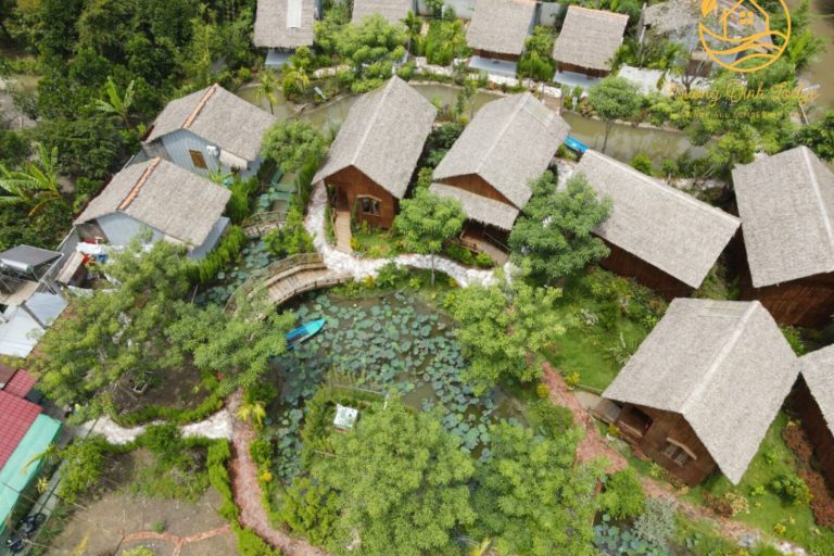 An aerial view of thatched bungalows around a lush garden at Mương Đình Lodge.