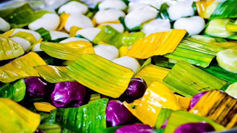 Small sweets in bright green, yellow and purple wrappers piled together.