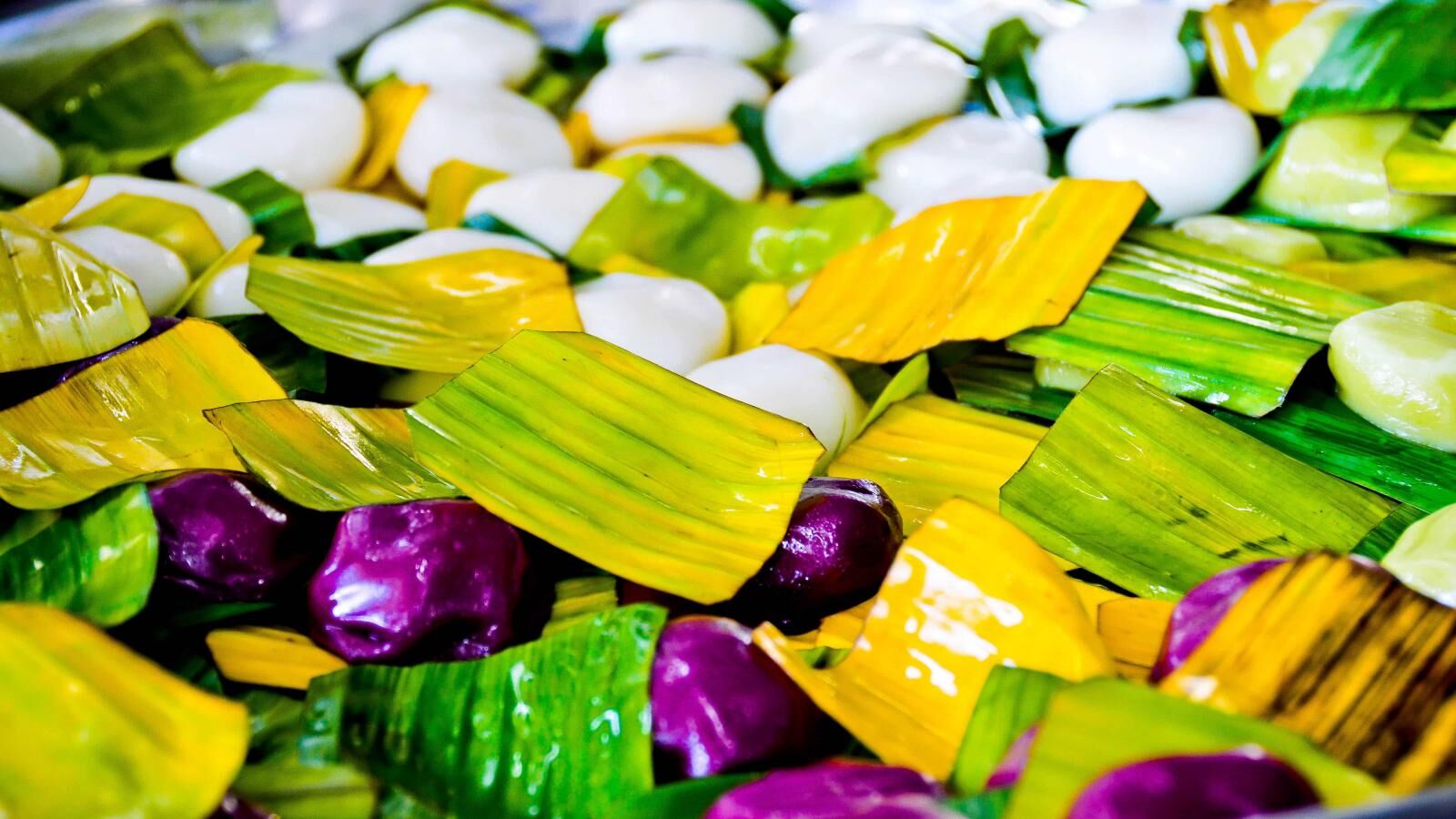 Small sweets in bright green, yellow and purple wrappers piled together.