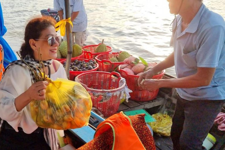 A woman holding a bag of fruit bought from a boat seller among baskets of produce.