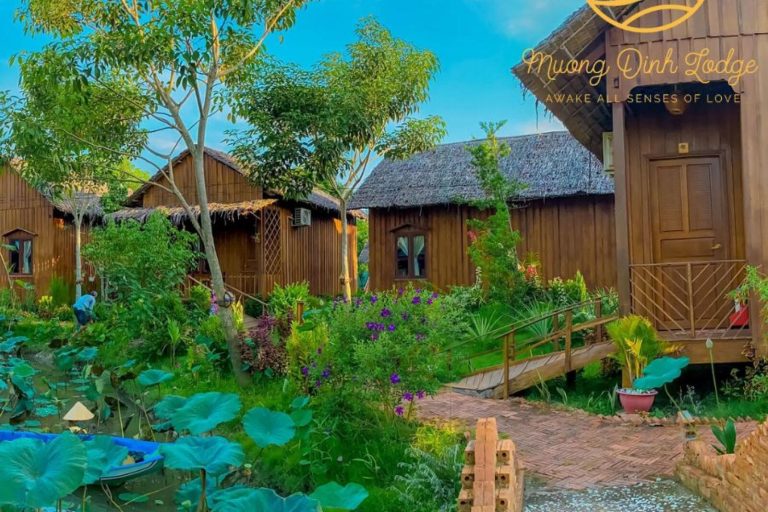 A lotus pond and brick path leading to the lodge's wooden cottages, with the lodge logo.