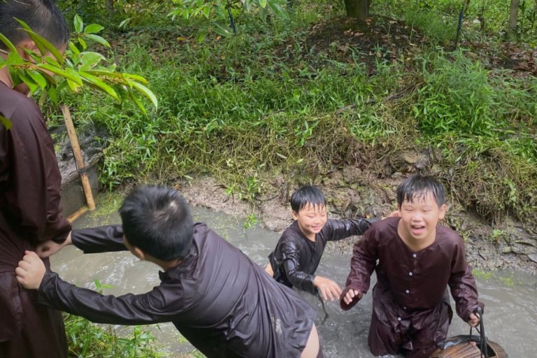 Trẻ em mặc bà ba nâu chơi đùa dưới con mương lầy bùn.