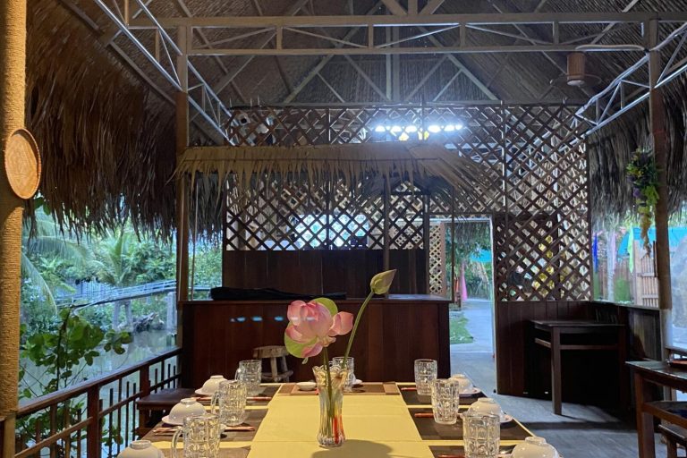 A table set with glasses and a lotus vase in the lodge's thatched restaurant.