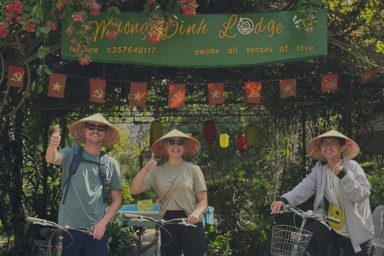 Three guests in conical hats with bicycles under the Mương Đình Lodge gate sign and red flags.