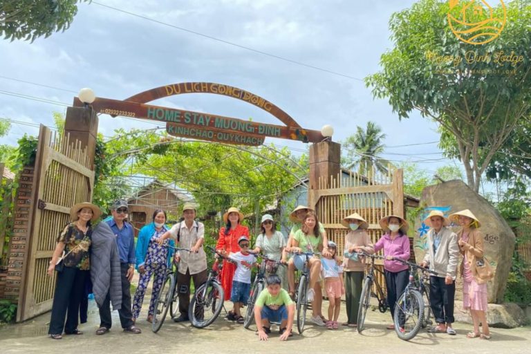 A group with bicycles posing under a wooden arched gate.