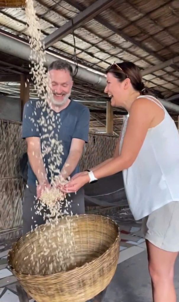 Two guests letting puffed grains pour through their hands into a bamboo basket.