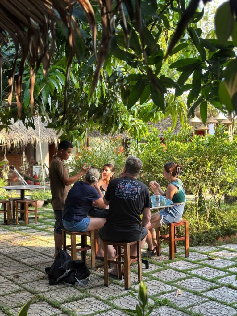 Guests sitting at small tables in a shaded garden courtyard.