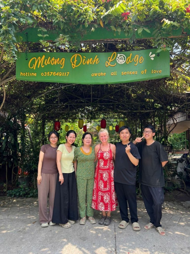 Six people standing together under the Mương Đình Lodge sign at the gate.