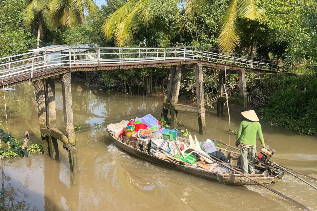 A boat vendor under a wooden footbridge.
