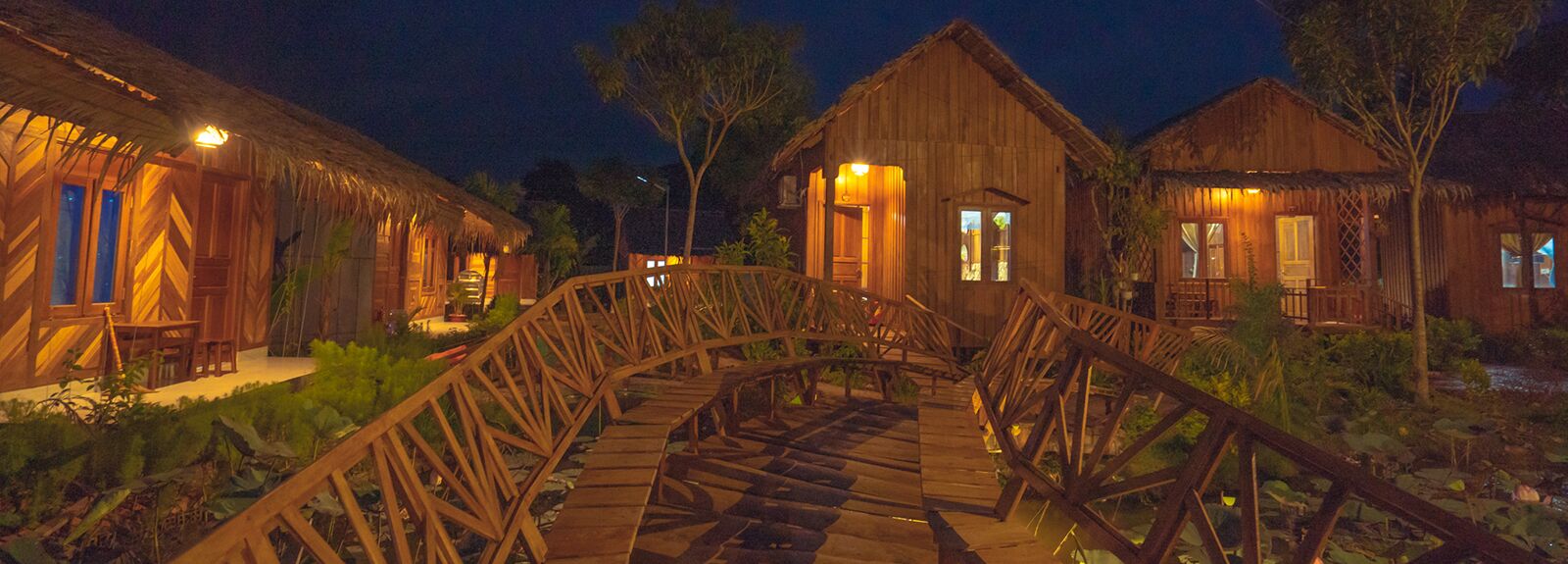 Wooden bungalows and the garden bridge lit up at night