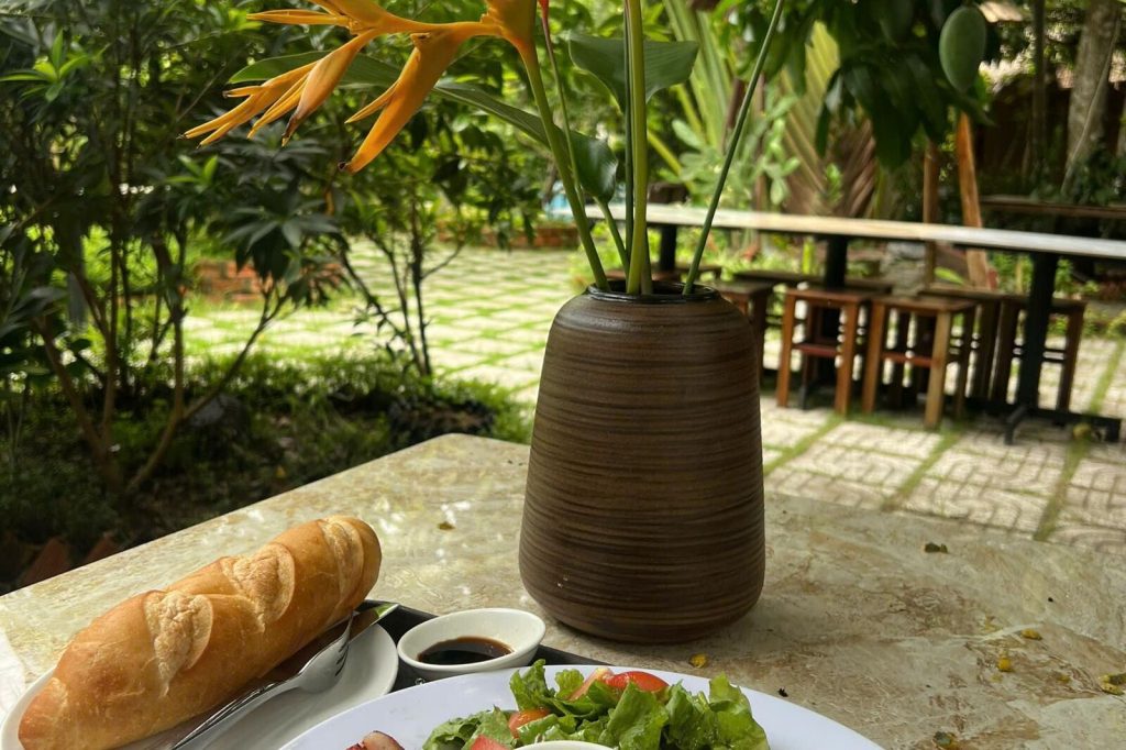 Baguette and drinks on a garden terrace table.