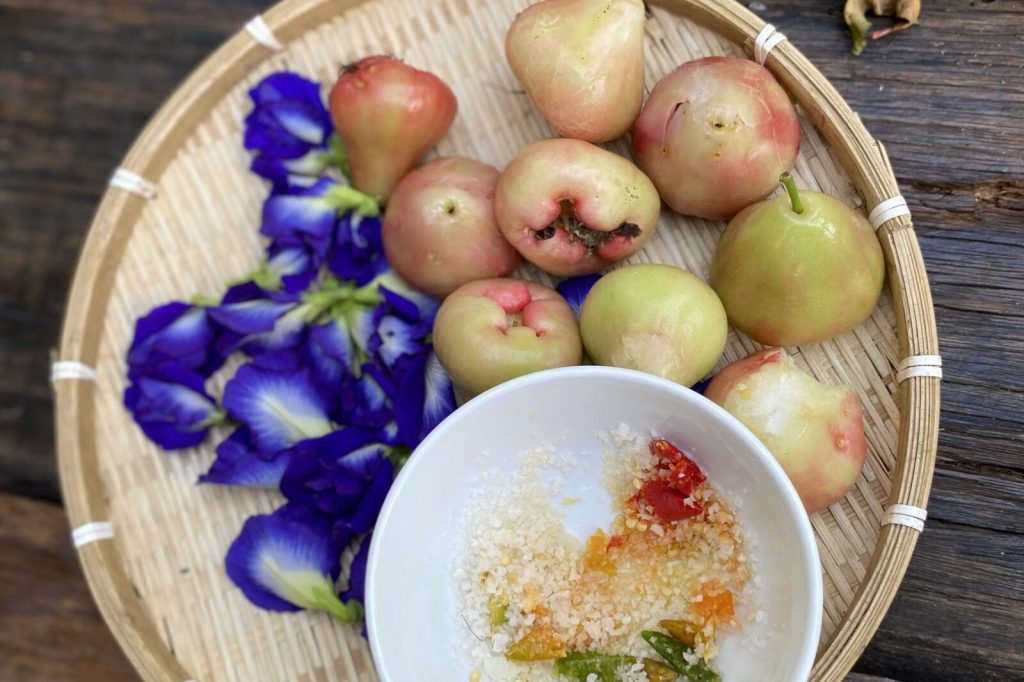 Basket of rose apples with butterfly pea flowers.