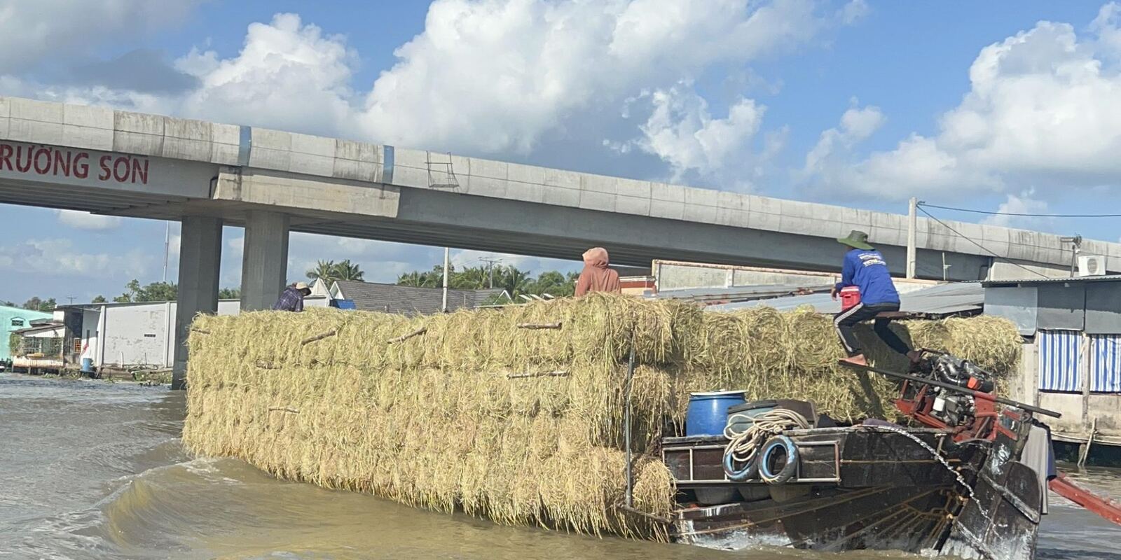 A boat loaded with straw passing under the bridge on the Xà No canal.